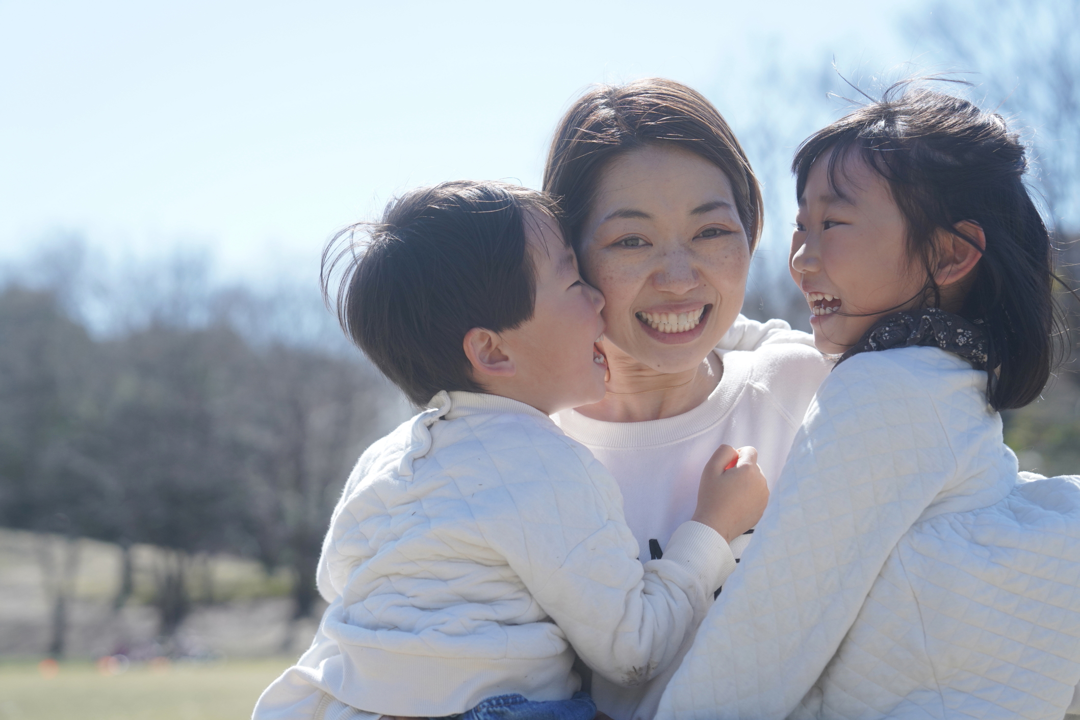 ママと子どもたちが抱き合うあたたかい家族写真